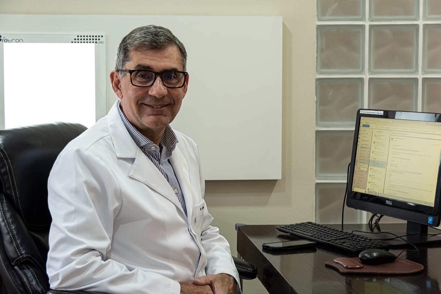 Dr. Carlos Del Roy em seu consultório no Itaim Bibi, sorrindo em retrato institucional.